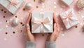 Womans hands holding gift or present box decorated confetti on pink pastel table top view. Flat lay composition for birthday or Royalty Free Stock Photo