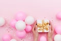 Womans hands holding gift or present box on pink pastel table decorated balloons and confetti. Flat lay composition. Royalty Free Stock Photo