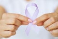 Womans hands holding purple domestic violence awareness ribbon Royalty Free Stock Photo