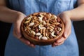 Womans hands holding a wooden bowl with mixed nuts. Healthy food and snack. Walnut, pistachios, almonds, hazelnuts and cashews. Royalty Free Stock Photo