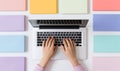 Womans hands on the laptops keyboard at the colorful office desk, flat lay Royalty Free Stock Photo