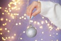 womans hands with nails holding christmas toy ball on a purple festive blurred bokeh background Royalty Free Stock Photo