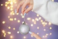 womans hands with nails holding christmas toy ball on a purple festive blurred bokeh background Royalty Free Stock Photo
