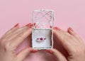 Womans hands opens a ornate gift box with a gemstone engatement ring on pink Royalty Free Stock Photo