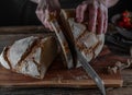 Slicing sourdough bread on a rustic and wooden cutting board. Royalty Free Stock Photo