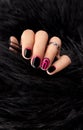 Womans hands with trendy pink and black manicure in fur coat