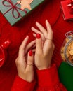 Womans hands with trendy red manicure with gift box on knitted blanket. Manicure, pedicure beauty salon concept.