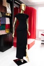 A womans long black dress on a Golden mannequin.