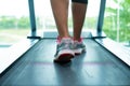 Womans muscular legs on treadmill in the gym, closeup.