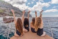 Womans on a yacht. Happy models in a swimsuit posing on a yacht against a blue sky with clouds and mountains