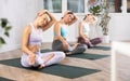 Women in activewear stretching muscles of neck before yoga training together in gym studio