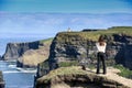 A women admires the Cliffs of Moher views, sea cliffs located at the southwestern edge of the Burren region in County Clare