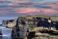 A women admires the Cliffs of Moher views, sea cliffs located at the southwestern edge of the Burren region in County Clare