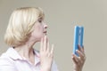 Women Ageing Concepts. Mature Caucasian Woman Examining Her Face In Hand Mirror And Examining Skin Indoors Royalty Free Stock Photo