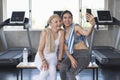 Women attractive smiling active fitness couple sitting in gym and taking a selfie