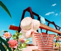 Women beach handbag and  sunglasses  straw hat  on bench at sea blue sky ,  tropical flowers white clouds  nature summer holiday b Royalty Free Stock Photo