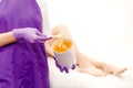 Women beautician holds jar of paste for sugar depilation shugaring, white background