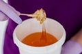 Women beautician holds jar wax of paste for sugar depilation shugaring, white background