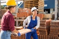 Women carrying flat hollow clay brick in outdoor warehouse