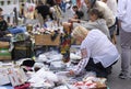 Women choosing handmade clothes placed on a pavement, street fair