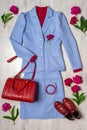 Women classic suit in blue color with red accessories and peonies on light background. Jacket and skirt with blouse Royalty Free Stock Photo