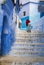 Women climbing a stair in the town of Chefchaouen in Morocco.