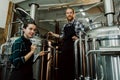 Women with clipboard working at brewery or beer plant. Brewery worker opening a lid of a beer cask at a craft beer Royalty Free Stock Photo