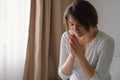 Women closed her eyes, praying in a in the living room. Hands folded in prayer concept for faith, spirituality and religion