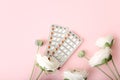Women contraceptive hormonal birth control pills blisters with flowers on pink background, close up
