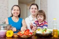 Women cook vegetables, while child eating salad