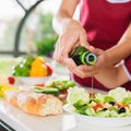 Women cooking fresh salad and pour olive oil. Healthy food