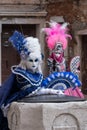 Masked women in costume with fans and ornate painted feathered masks at Venice Carnival.
