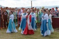 Women in costumes dancing on the grass in front of the audience during the ethnic festival Karatag on the shore of a Large lake