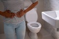 Women with Cystitis problems in front of the toilet bowl handle the belly want to pee , concept of incontinence Royalty Free Stock Photo