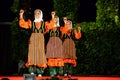 Women dancing using wooden spoons at folklore festival stage
