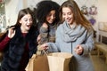 Women of diverse ethnicity with shopping bags posing in clothing store. Portrait of three smiling multiracial girls Royalty Free Stock Photo