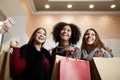 Women of diverse ethnicity with shopping bags posing in mall on sale. Portrait of three smiling multiracial girls look Royalty Free Stock Photo