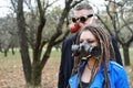 A woman with dreadlocks and a gas mask and a man with steampunk goggles and a gas mask look at the camera and pose in Royalty Free Stock Photo