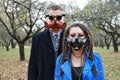 A woman with dreadlocks and a gas mask and a man with steampunk goggles and a gas mask look at the camera and pose in Royalty Free Stock Photo