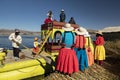 Women dressed in colorful clothes say goodbye to tourists traveling in totora on Lake Titicaca. Peru