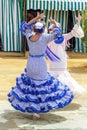 Women dressed in colourful flamenco dresses and dancing at the Seville April Fair.