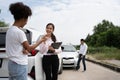 Women drivers Talk to Insurance Agent for examining damaged car and customer checks on the report claim form after an accident.