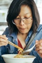 Women eating egg noodle with crispy pork from chopsticks and met