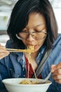 Women eating egg noodle with crispy pork from chopsticks and met