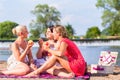 Women eating fruit at river beach picnic