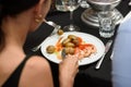 women eating traditional spanish tapas served on plates on black table background. Patatas Bravas with Gambas Ajillo