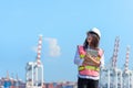 The women engineer holding laptop and working with container Cargo freight ship in shipyard at dusk for Logistic Import Export bac