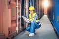 Women Engineer wears PPE checking container storage with cargo container background at sunset. Logistics global import or export