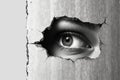 Women Eye peeping through hole in concrete wall. Black and white Royalty Free Stock Photo