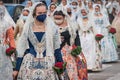 Women with face masks and traditional floral dresses walking for the parade at the celebration `Fallas`, Valencia, Spain